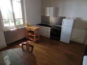 a kitchen with a table and a white refrigerator at Appartement indépendant dans grande maison in Pouilly-sur-Loire