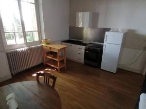 kuchnia ze stołem i białą lodówką w obiekcie Appartement indépendant dans grande maison w mieście Pouilly-sur-Loire +10 zdjęć