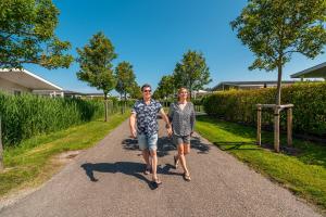 a man and a woman walking down a road at Comfort Rooms by EuroParcs Schoneveld in Breskens