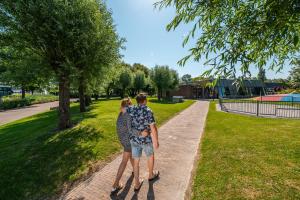 a man and a woman standing in a park at Comfort Rooms by EuroParcs Schoneveld in Breskens