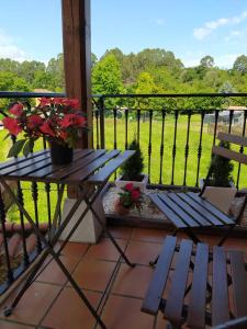 - une terrasse couverte avec un banc et une table fleurie dans l'établissement LA GRANDA DE LA CONCHA, à Nueva de Llanes
