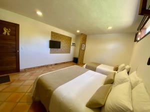 a bedroom with two beds and a flat screen tv at Hotel Alandalus in Villa de Leyva