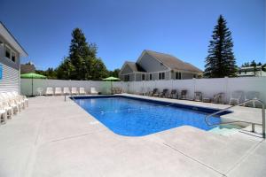 a swimming pool with chairs and a white fence at Killington Center Inn & Suites by Killington VR - 1 Bedrooms in Killington
