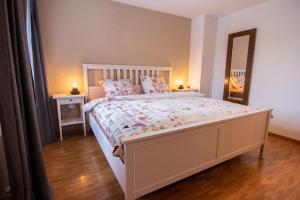 a bedroom with a large white bed and a mirror at Ferienwohnung Frostenegg 