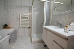 a white bathroom with a tub and a sink and a shower at Ferienwohnung Frostenegg 