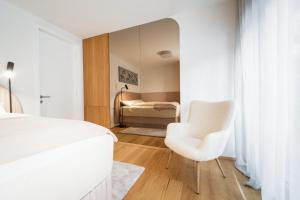 a bedroom with a white bed and a white chair at Bor in Bor Luxury Apartment with sauna & garden - Kranjska Gora in Kranjska Gora