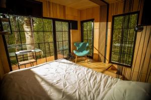 a bedroom with a bed and a chair and windows at Domek na drzewie - Na Łośmiu Metrach in Grudki