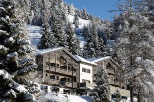a building in the snow with snow covered trees at Hotel Schmung in Alpe di Siusi