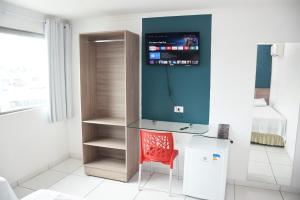 Cette chambre comprend un bureau en verre et une chaise rouge. dans l'établissement Hotel Center Vitoria, à Vitória de Santo Antão