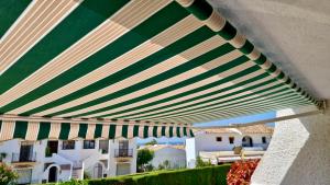 un ombrello verde e bianco da patio con edifici sullo sfondo di RIVIERA PLAYA 200m to the beach in Riviera del Sol, Mijas Costa a Sitio de Calahonda