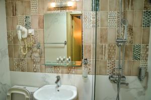 uma casa de banho com um lavatório e um chuveiro com um espelho. em Villa ARS em Belgrado