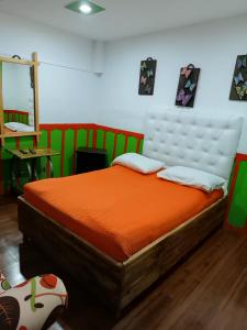 1 dormitorio con 1 cama grande de color naranja y cabecero blanco en Hostel Camelot Salento, en Salento
