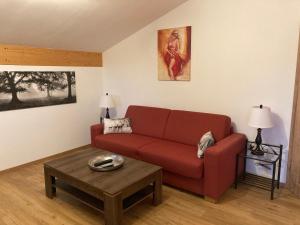 ein Wohnzimmer mit einem roten Sofa und einem Tisch in der Unterkunft Ferienwohnung Gruberhof in Rimsting