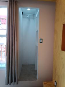 Zimmer mit einem Spiegel, einem Vorhang und einem Fenster in der Unterkunft PentHouse con Roof Garden Privado Aeropuerto CDMX in Mexiko-Stadt