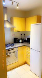 a kitchen with yellow cabinets and a white refrigerator at Solonzo apartment in North Woolwich