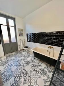a bathroom with a tub and a tile floor at Carcassonne Bastide in Carcassonne