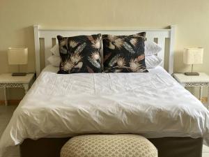 a white bed with two pillows on top of it at Beacon Stay Beach Studio Apartment in Summerstrand
