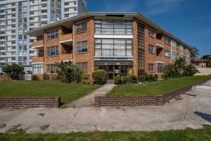 a large brick building in front of a tall building at Beacon Stay Beach Studio Apartment in Summerstrand