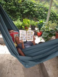 Casa Pé di Polon holiday home في Picos: رجل يستلقي على أرجوحة يقرا كتاب