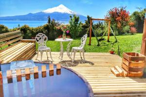 a wooden deck with a table and chairs and a mountain at Refugio y tinajas Vientos del lago in Los Riscos
