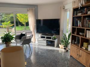 ein Wohnzimmer mit einem Flachbild-TV und Bücherregalen in der Unterkunft Magnifique Villa au cœur de l’Yonne in Auxerre