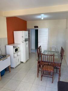 eine Küche mit einem Tisch und Stühlen sowie einem weißen Kühlschrank in der Unterkunft Apartamento itapirubá in Imbituba