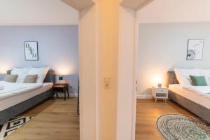 1 dormitorio con 2 camas y pasillo en DWELLSTAY - Wohnung 90qm, 3 Schlafzimmer, Küche, Wohnzimmer, Balkon, Netflix, en Fulda