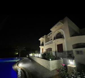 a large white house at night with a swimming pool at Villa elzaher in Qaryat Shākūsh