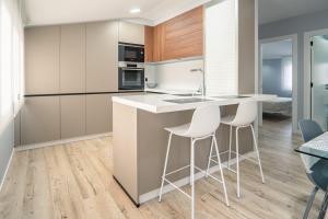 a kitchen with white counter chairs and a kitchen island at APARTAMENTO PEDRADOURO in Malpica
