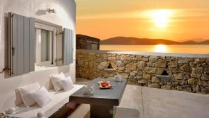 a living room with a table and a stone wall at Tohu Villas Mykonos in Ornos
