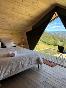 a bedroom with a bed and a large window at Cúspide Lodge - Choachí in Choachí