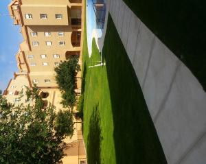 a building with a green lawn next to a building at GRANJA-CLIMATIZADO-Parking gratis in Jaén