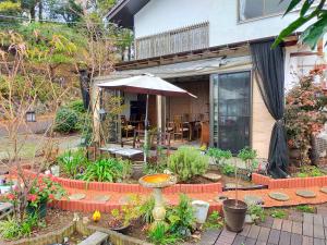 un patio con sombrilla y algunas plantas en Pension Izukogen, en Ito