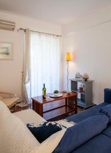 Blue Apartment 2nd floor feel like home properties في Saronida: غرفة معيشة مع أريكة زرقاء وطاولة