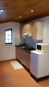 a kitchen with a white refrigerator and a microwave at A casa da serra - alojamento local in Casal Velho