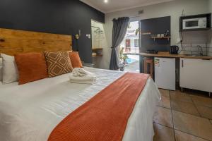a bedroom with a large white bed and a kitchen at Boma Lodge in Durban
