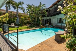 una piscina en el patio trasero de una casa con palmeras en Boma Lodge, en Durban