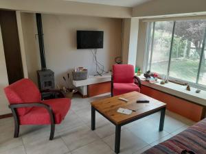 una sala de estar con 2 sillas rojas y una mesa. en AMORADA en Potrerillos