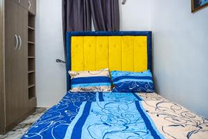 a bed with a blue and yellow headboard in a room at Admirable 2-bed-Apt With Pool, 24hrs Power & Unlimited Internet in Amuwo