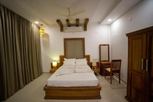 a bedroom with a bed and a table and a chair at OPM INN in Payyannūr
