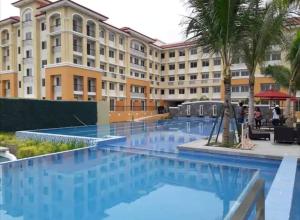 a hotel with a swimming pool in front of a building at 2BR Casa Mia Sanremo Oasis Cebu in Talisay