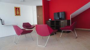 Cette chambre dispose de 4 chaises, d'une télévision et de murs rouges. dans l'établissement Chalet Madonna di Viggiano, à Viggiano