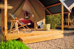 ein Zelt mit einem Bett und einem Stuhl darin in der Unterkunft Camping Du Paquier Fané in Chagny