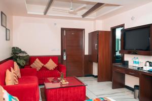 a living room with a red couch and a tv at The Fern Residency Katra in Katra