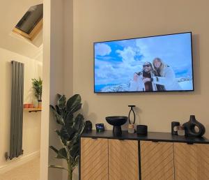 a flat screen tv on a wall with two women at Stylish, Comfortable Coach House in Falmouth