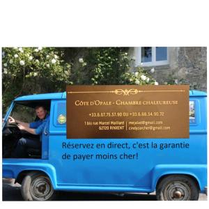 Una mujer conduciendo una furgoneta azul con un cartel. en Côte d Opale - Chambre cocooning en Rinxent