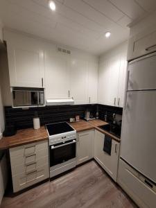 a kitchen with white cabinets and a stove top oven at Topelius Park Apartment in Uusikaarlepyy