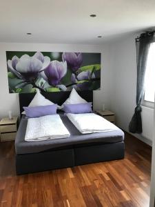 1 dormitorio con 1 cama con una pintura de flores púrpuras en Ferienwohnung Romantica 1. und 2. OG en Schopfloch