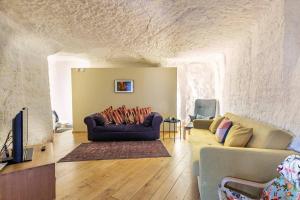 a living room with a couch and a tv at Le Chai Raffiné: an old-school winery renovated for modern holidays in Rochecorbon