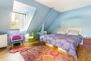 a bedroom with a purple bed and a pink chair at Le Chai Raffiné: an old-school winery renovated for modern holidays in Rochecorbon